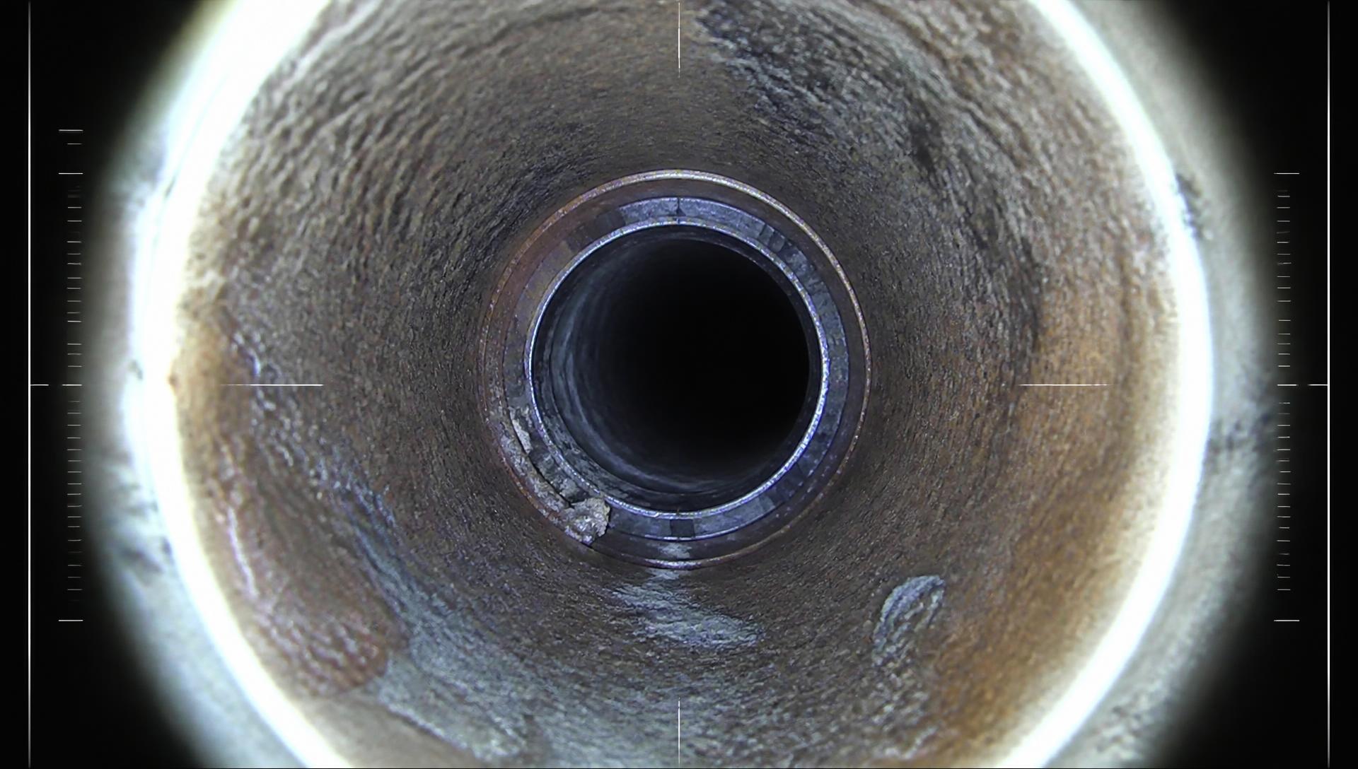 Downhole camera still inside corroded steel well casing showing a casing collar and scale buildup